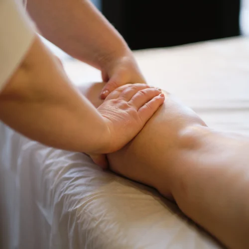 Stock image of a person massaging their leg, representing manual treatment for edema and swelling reduction